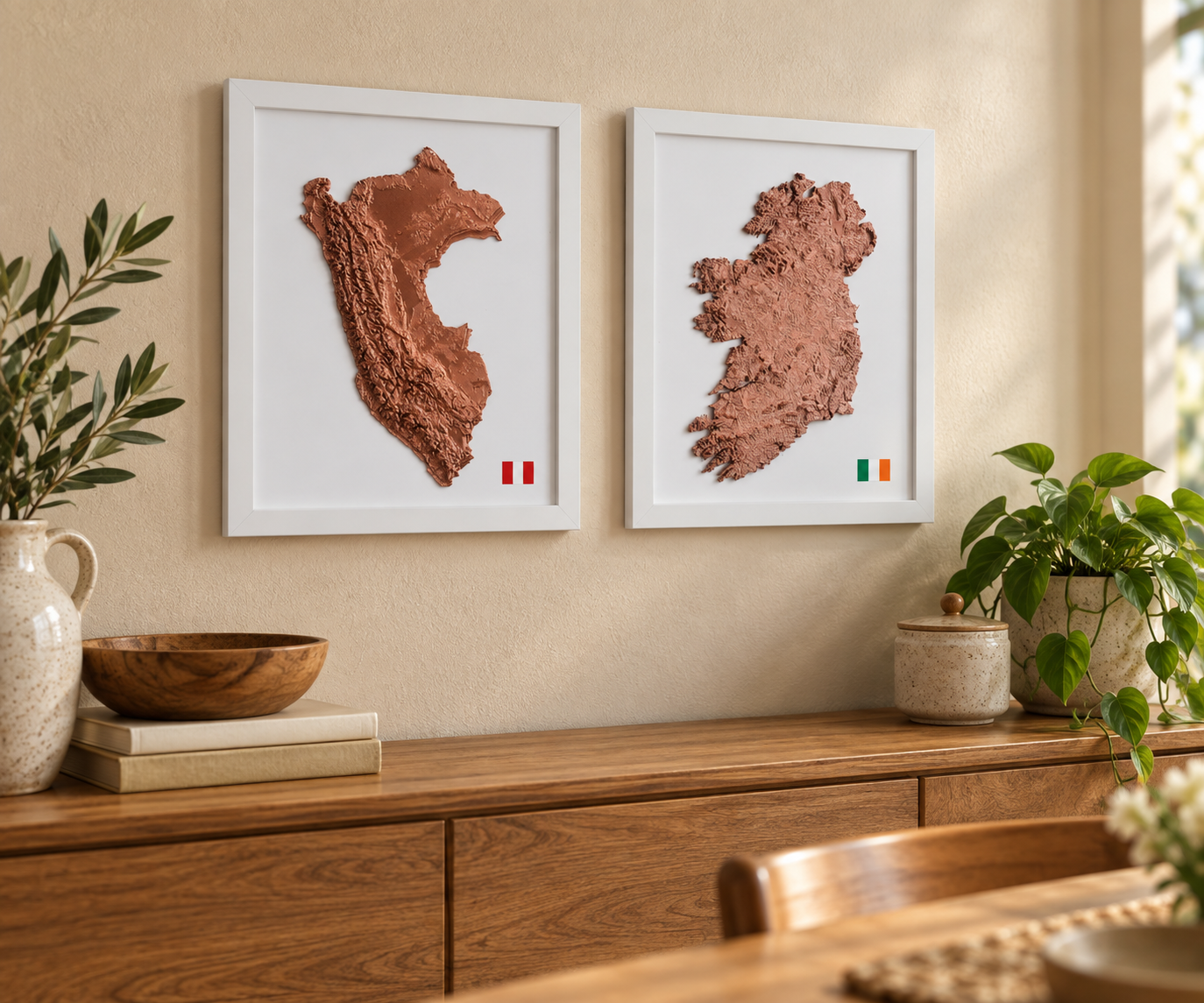 Copper relief maps of Peru and Ireland in white frames above an oak sideboard